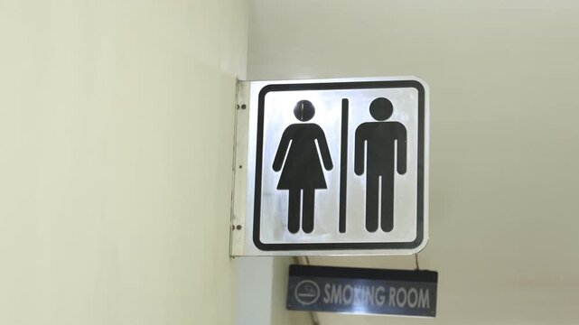 Male and Female Restroom Symbols hanging on the Wall. Gender-specific bathroom signs in black colour.
