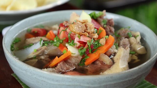 Oxtail soup (sop buntut). Made from pieces of beef tail that are seasoned then put in a slightly beef broth with sliced potatoes, carrots, tomatoes, celery. Indonesian traditional culinary
