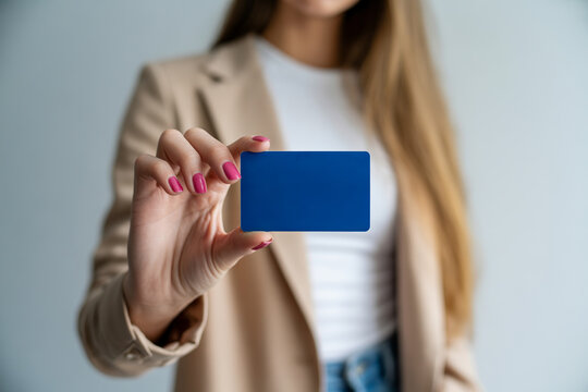 Woman presenting a blank blue card focusing on hand and business attire.