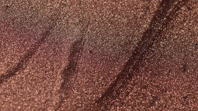 Detailed shimmering close-up of rose gold paint specialized sandy texture and radiant glitter particles on surface