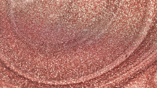 Rotating view of rose gold paint with specialized sandy texture and radiant glitter particles forming circular waves