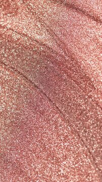 Dynamic vertical rotating close-up of rose gold paint specialized sandy texture and radiant glitter particles on surface