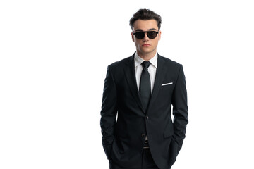 Cool elegant man in black suit holding hands in pockets