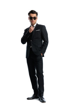Confident man with hand in pocket adjusting tie
