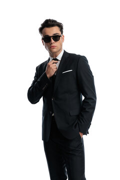 Elegant man adjusting tie and posing with hand in pocket