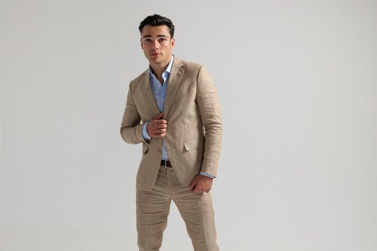 Confident man wearing beige suit adjusting jacket