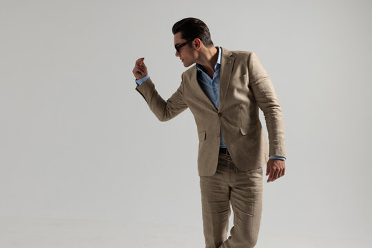 Confident man in beige suit snapping fingers looking to side