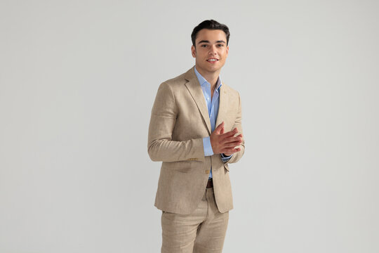 Charming man rubbing hands together in beige suit