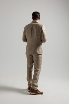 Rear view of stylish man standing wearing beige suit