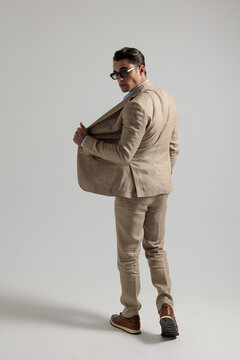 Back view of trendy man walking away looking back
