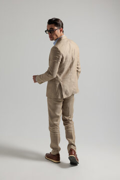 Rear view of stylish man walking away looking back