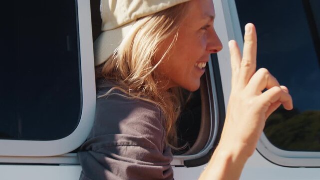 Happy woman sits in the bus and shows the peace sign looking into the camera