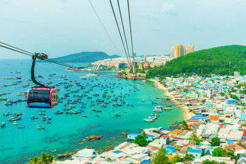 Cable car cabin traveling above turquoise water and fishing boats near An Thoi harbor on Phu Quoc island, Vietnam. Island transportation and tourism infrastructure Modern Hon Thom cable car gondolas © samael334