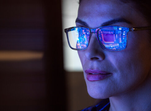 Woman with computer chip reflection in glasses representing artificial intelligence