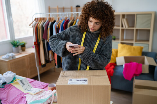 Entrepreneur photographing package for ecommerce shipping in home office