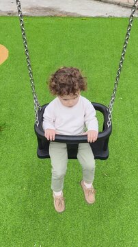 Ni&ntilde;o jugando seguro en columpio cerrado elevado en parque infantil moderno