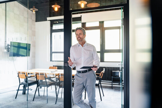 Portrait of confident business leader with tablet in modern office