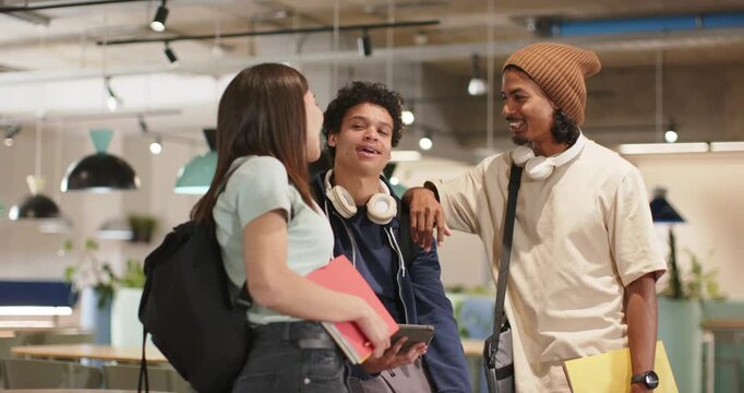 African American friends holding tablet and pointing, reacting to funny content in study lounge