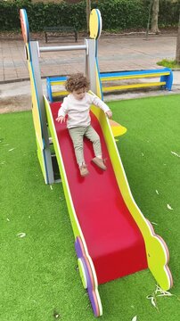 Ni&ntilde;o jugando solo en tobog&aacute;n de parque infantil moderno y seguro