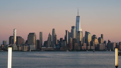 Obraz premium New York City Manhattan Downtown Financial District skyline, World Trade Center tower skyscraper from New Jersey, Hoboken pier, United States. River waterfront urban cityscape, evening dusk twilight.