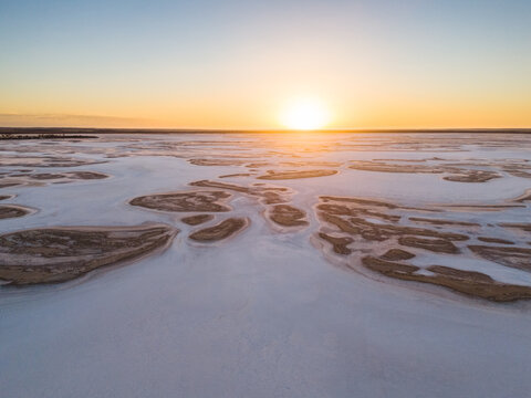 Aerial view of the stark white salt flats contrasting with the golden sunset over Lake Campion Nature Reserve, Lake Campion, Western Australia, Australia.