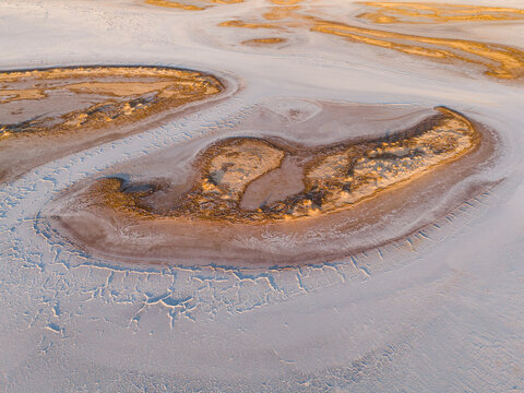 Aerial view of the stark white expanse of Lake Campion, broken by islands of golden earth and dry vegetation, Lake Campion Nature Reserve, Western Australia, Australia.