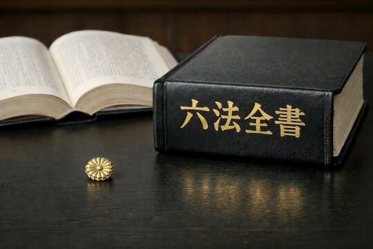 日本の法律を象徴する六法全書と机の上に置かれた弁護士バッジが重厚な雰囲気を醸し出す写真