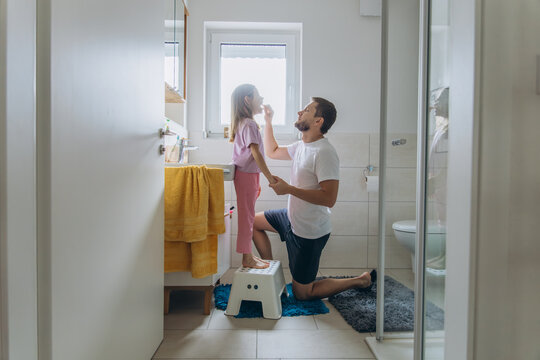 Father and daughter in bathroom checking loose tooth in morning routine
