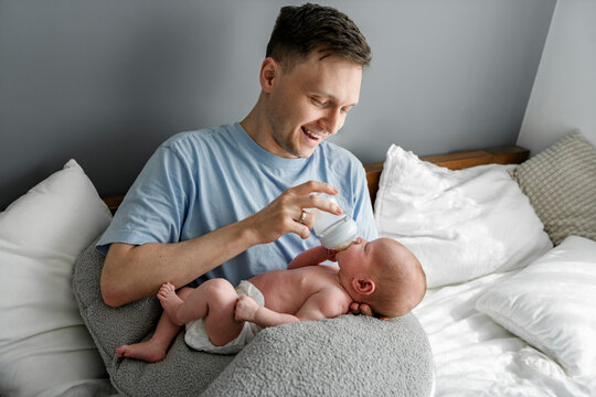 Father bottle-feeding baby and bonding at home in bedroom
