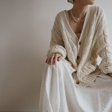 Elegant casual outfit with cream knit cardigan and linen skirt, soft texture close up