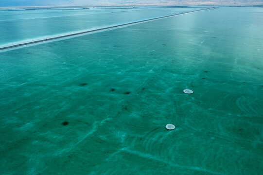 Aerial view of the mesmerizing turquoise waters of the Dead Sea, with dark mineral deposits creating striking patterns, Arad, South District, Israel.