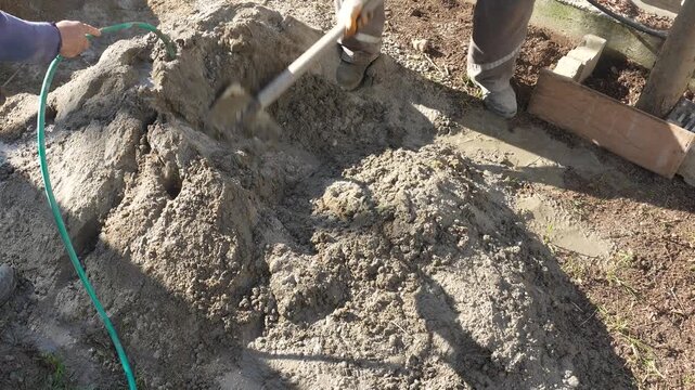 DIY Construction: Worker Mixing Concrete with Shovel in Garden for Flat Surface. High quality 4k footage