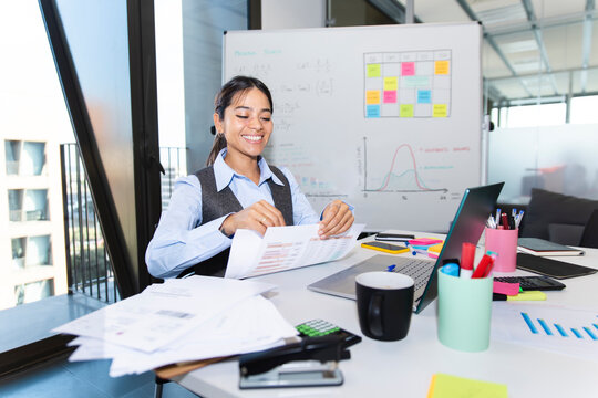 Smiling employee analyzing documents at desk in modern office