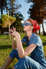 lifestyle woman in modern boho-western denim street style with blue sunglasses and red bandana...