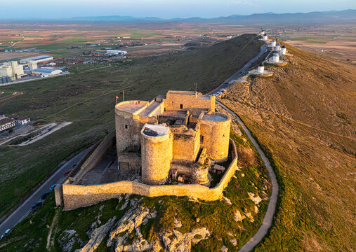 Aerial view of the imposing Castillo de Consuegra basking under the golden light, with windmills lining the horizon, Consuegra, Castilla-La Mancha, Spain.