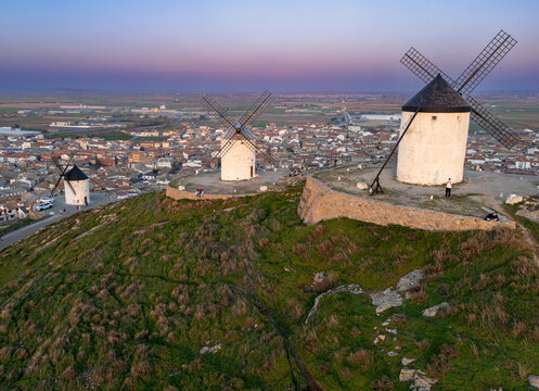 Aerial view of windmills standing proudly atop a hill overlooking the town, bathed in the soft glow of the setting sun, Consuegra, Castile-La Mancha, Spain.