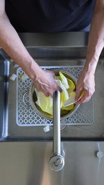 Person washing and peeling fresh endives in a modern kitchen sink.Vertical video