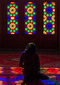 Iranian woman praying in the nasir ol molk mosque with its beautiful coloured glass windows, Fars province, Shiraz, Iran