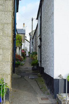 A narrow street lined with flower pots in the picturesque fishing village of Mousehole, on the south coast of Cornwall, England