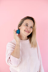 Naklejka premium Blonde woman with blue massage ball in front of pink background