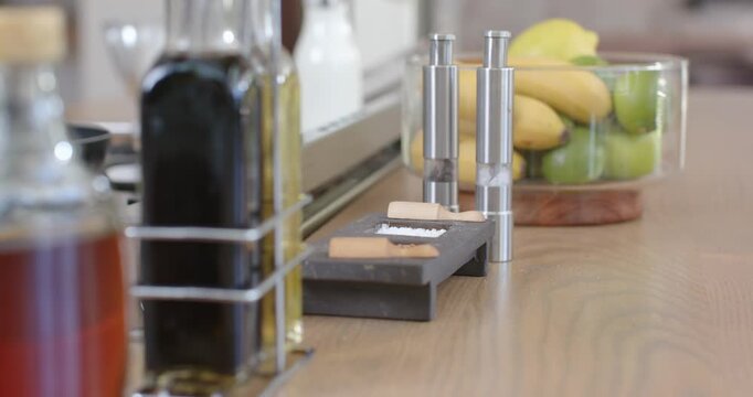 Camera is shifting right and focusing on steel grinders and salt tray to reveal kitchen condiments