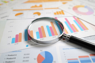 Plakat Magnifying glass on graph paper, charting financial developments, statistics, and analytical research data for investment or stock market trading , corporate meeting ideas, business office.