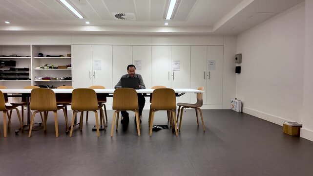 Layoffs And Corporate Downsizing South Asian Male Alone In Empty Office Working At Table.