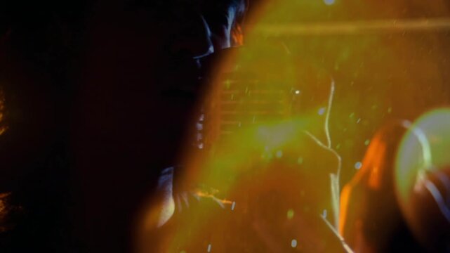 Lead singer starting singing on music set holding retro mic film burn flare sweeping obscuring face
