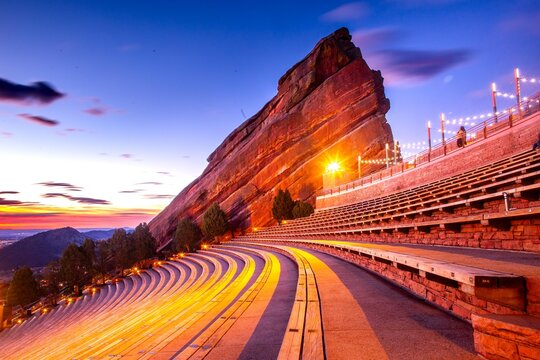 View of Red Rocks Amphitheatre's iconic sandstone formations bathed in the glow of twilight and stage lights, Morrison, Colorado, United States.