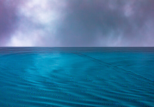 Rippled swimming pool surface in rain under dramatic cloudy sky outdoors