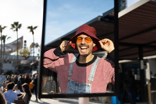 Smiling person wearing sunglasses and red hat posing outdoors in summer