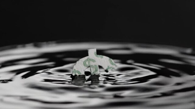 Dollar sign made of paper floats on water surface, creating ripples and reflections, showcasing the concept of money and value in a visually striking manner