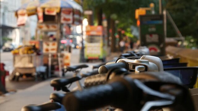 Manhattan Midtown street New York City, United States. Rental bicycle parking, Central Park West summer trees greenery. Bike for rent in row. People pedestrian on sidewalk pavement. Hot dog fast food.