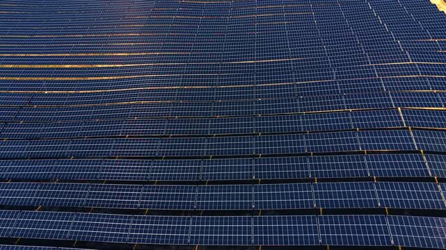 Top down aerial view of many solar panel rows. High angle vertical perspective of photovoltaic modules arranged in parallel lines covering the ground.